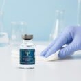 A laboratory researcher wearing blue nitrile gloves preparing a sterile workspace next to a 10mg vial of Resurrection Peptide Melanotan II, highlighting professional research standards and cleanroom protocols.