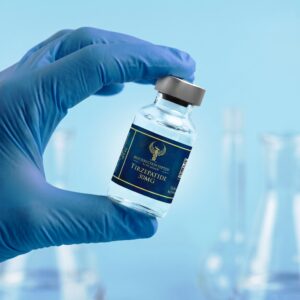A close-up shot of a scientist's hand in a blue nitrile glove holding a 30mg vial of Tirzepatide by Resurrection Peptide, with a blurred laboratory setting and erlenmeyer flasks in the clinical background.